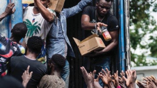 Men hand out supplies to a crowd of earthquake victims during the distribution of food and water at ...