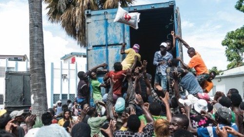 TOPSHOT - A man throws a bag of rice into a crowd of earthquake victims gathered for the ...