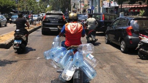 A man rides his scooter with empty water bottles to fill them with gasoline, in Beirut, Lebanon, ...