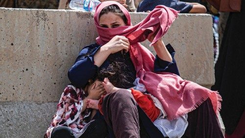 A woman and children wait for transportation to the terminal at Hamid Karzai International Airport, ... A woman and children wait for transportation to the terminal at Hamid Karzai International Airport, ...