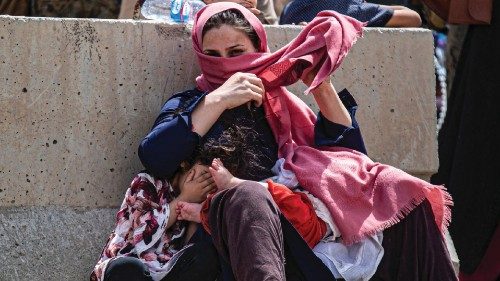 A woman and children wait for transportation to the terminal at Hamid Karzai International Airport, ...