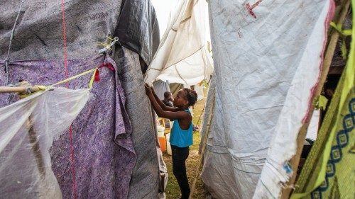 A girl helps secure her family's tent at an encampment set up on a soccer field after the August 14 ...