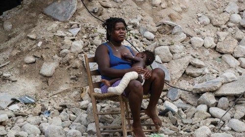 epa09425602 Altermard Roselina holds her son Andel Lovenia Lovensky in her arms next to the ruins of ...