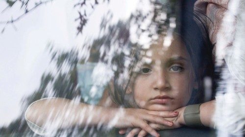 A girl looks out the front window of a bus as she and other people arrive at a processing center for ...