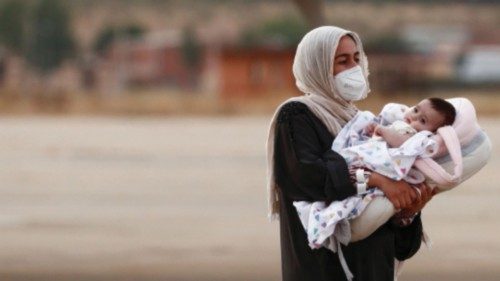 An Afghan woman who has been evacuated from Kabul carries a child as she arrives at Torrejon Air ...