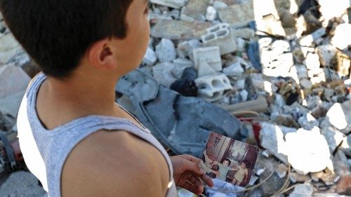 TOPSHOT - A boy holds a personal photo print showing children as he stands by rubble in the ...