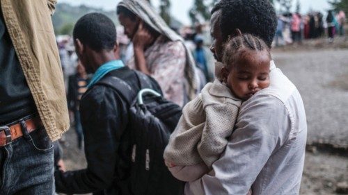 A man holds a baby during a food distribution for internally displaced people (IDPs) from Amhara ...