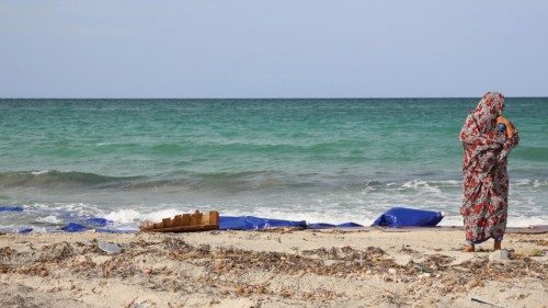 A Libyan woman stands next to the remains of a dingey and life jackets that washed up on the  beach ...