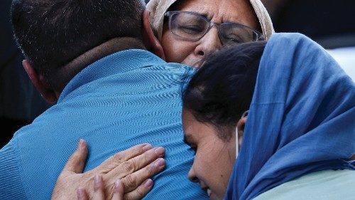 Afghan refugees embrace family before boarding buses that will take them to a processing center ...