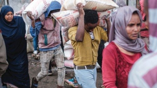 Youngsters carry sacks of rice during a food distribution for internally displaced people (IDPs) ...