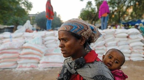 FILE PHOTO: A woman carries an infant as she queues in line for food, at the Tsehaye primary school, ...