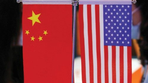 Staff members chat behind Chinese and U.S. flags displayed at the 2021 China International Fair for ...