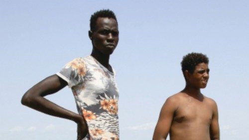 A Sudanese (R) and a southern Sudanese refugee stand in flood waters in the al-Qanaa village in ...