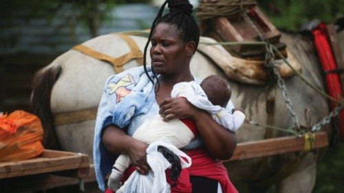 A migrant holds a child while preparing to cross into Panama and continue north, in Acandi, Colombia ...