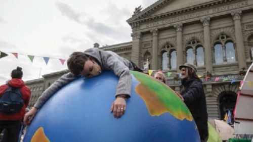 A climate activist lays on an inflatable world globe in front of the Swiss House of Parliament at ...