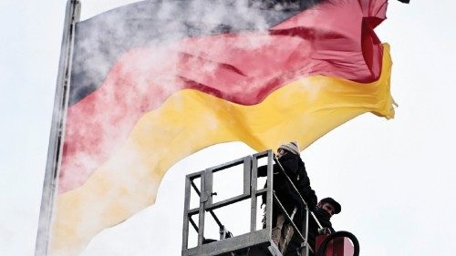 Workers are seen in front of a German flag on top of the Reichstag building in Berlin, Germany, ...