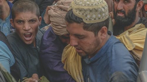 TOPSHOT - Carriers rush to pass towards the border gate to Pakistan from the Afghanistan border in ...