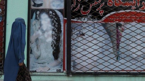 A woman walks past a shop with defaced pictures of women in Kabul, Afghanistan October 6, 2021. ...