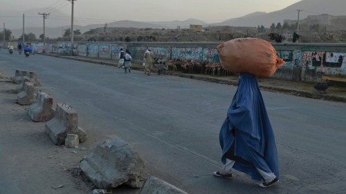 A burqa-clad woman carrying a sack walks along a street in Kabul on October 8, 2021. (Photo by ...