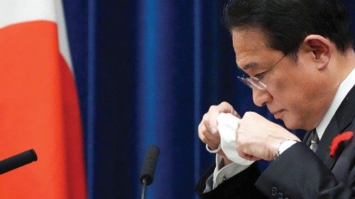 Japanese Prime Minister Fumio Kishida puts on his protective mask after speaking during a news ...