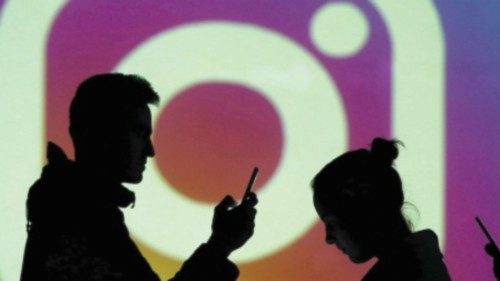 FILE PHOTO: Silhouettes of mobile users are seen next to a screen projection of Instagram logo in ...