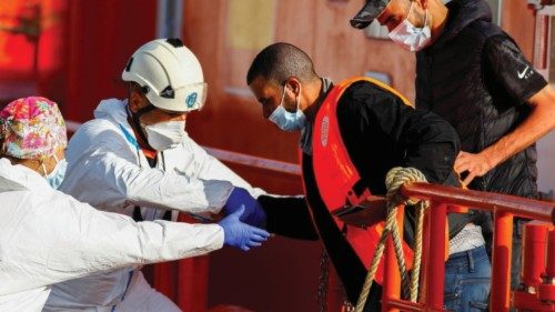 Rescuers help a migrant to disembark from a Spanish coast guard boat in the port of Arguineguin, on ...