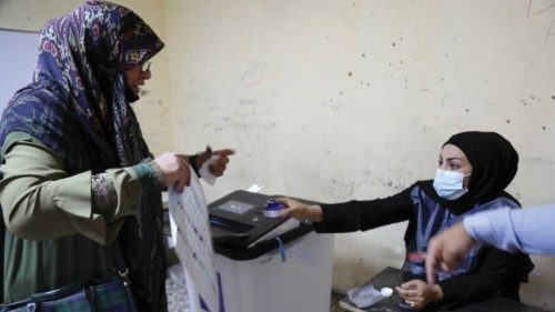 epa09516109 An Iraqi elderly woman casts her ballot during the parliamentary elections at a polling ...