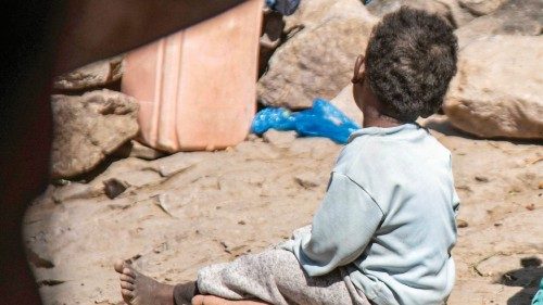 Children sit on the ground by a cave where a Yemeni family has sought refuge due to poverty and lack ...