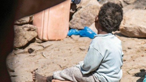 Children sit on the ground by a cave where a Yemeni family has sought refuge due to poverty and lack ...