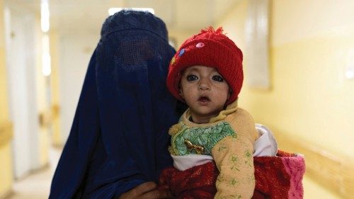 A mother wearing a burqa walks with a baby at the malnutrition ward at the Indira Gandhi hospital in ...