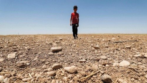 (FILES) In this file photo taken on June 24, 2021, a boy walks through a dried up agricultural field ...