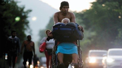 A migrant man pushes his mother's wheelchair as they take part in a caravan heading to Mexico City, ...