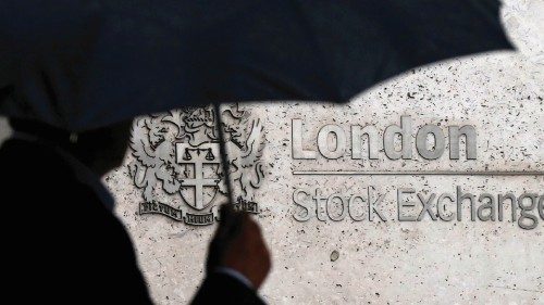 FILE PHOTO: A man shelters under an umbrella as he walks past the London Stock Exchange in London, ...