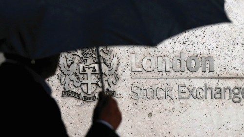 FILE PHOTO: A man shelters under an umbrella as he walks past the London Stock Exchange in London, ... FILE PHOTO: A man shelters under an umbrella as he walks past the London Stock Exchange in London, ...