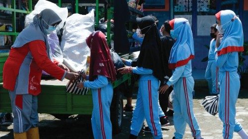 Students line up with their plastic waste to exchange for a borrowed book on the mobile library at a ...