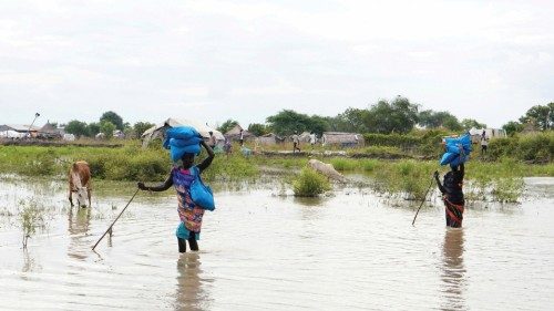 FILE PHOTO: Women carry sacks on their heads as they walk through water, after heavy rains and ... FILE PHOTO: Women carry sacks on their heads as they walk through water, after heavy rains and ...
