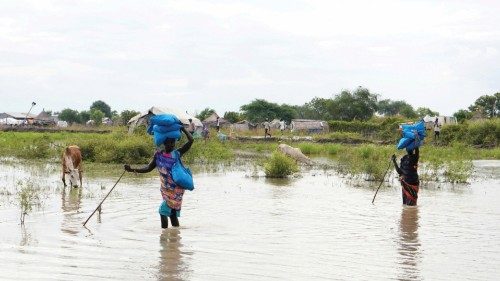 FILE PHOTO: Women carry sacks on their heads as they walk through water, after heavy rains and ...