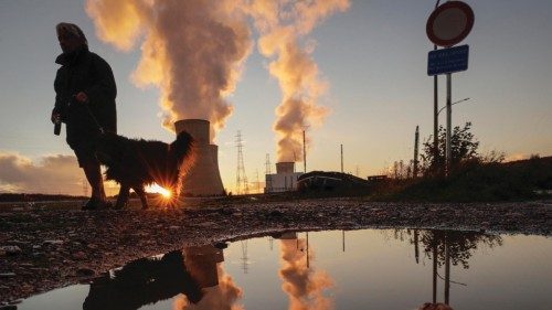 epa09559894 A woman walks with a her dog as sun sets over the Engie nuclear power plant in Tihange, ...