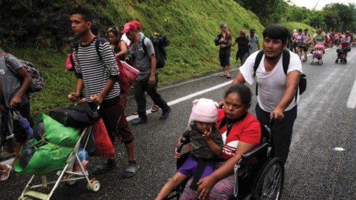 A migrant man pushes a woman and a child in a wheelchair as they take part in a caravan heading to ...