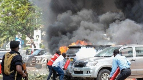 People extinguish fire on cars caused by a bomb explosion near Parliament building in Kampala, ...