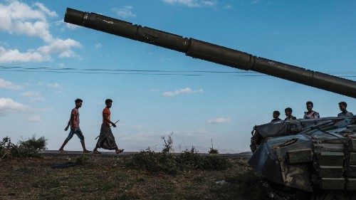 (FILES) In this file photo taken on December 11, 2020 Youngsters walk next to an abandoned tank ...
