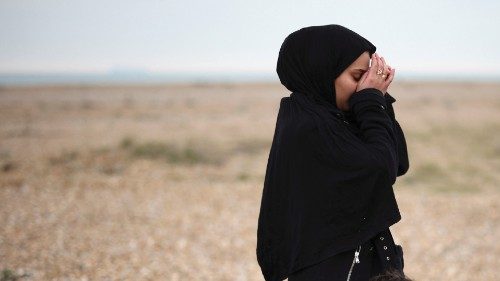 A migrant woman with a child reacts after being brought ashore by a RNLI Lifeboat, after having ...