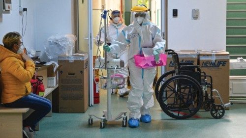 Medical personnel passes by a waiting Covid-19 patient (L) to be hospitalized at the ...