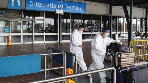 Travellers in personal protective equipment depart the international terminal for a taxi stand at ...