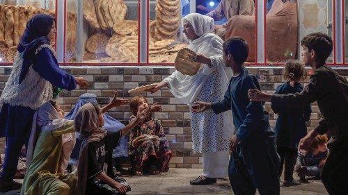 TOPSHOT - A woman gives bread to young people in need in front of bakery in Kabul on September 19, ...