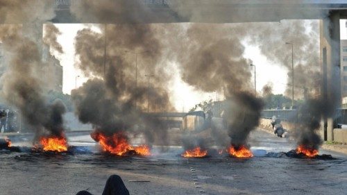 TOPSHOT - A Lebanese protester lies on a street blocked with burning tyres during a protest in the ...
