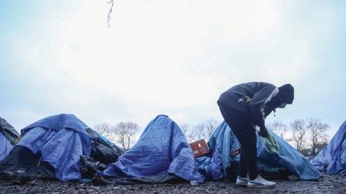 epa09607213 A Sudanese migrant prepares to enter his tent in Calais, France, 27 November 2021. At ...