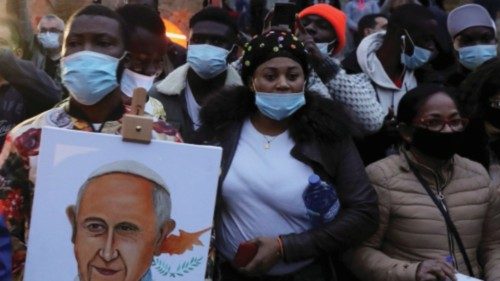 People stand near a sign with an image depicting Pope Francis, outside the Parish Church of the Holy ...