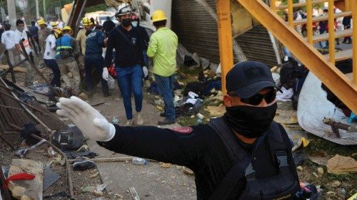 A police officer raises his arm to block photographers to to avoid taking pictures at the site of a ...