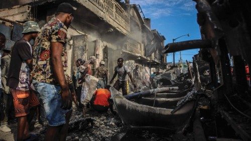 TOPSHOT - Men pick up aluminum pieces at the site where a tanker truck exploded in Cap-Haitien, ...